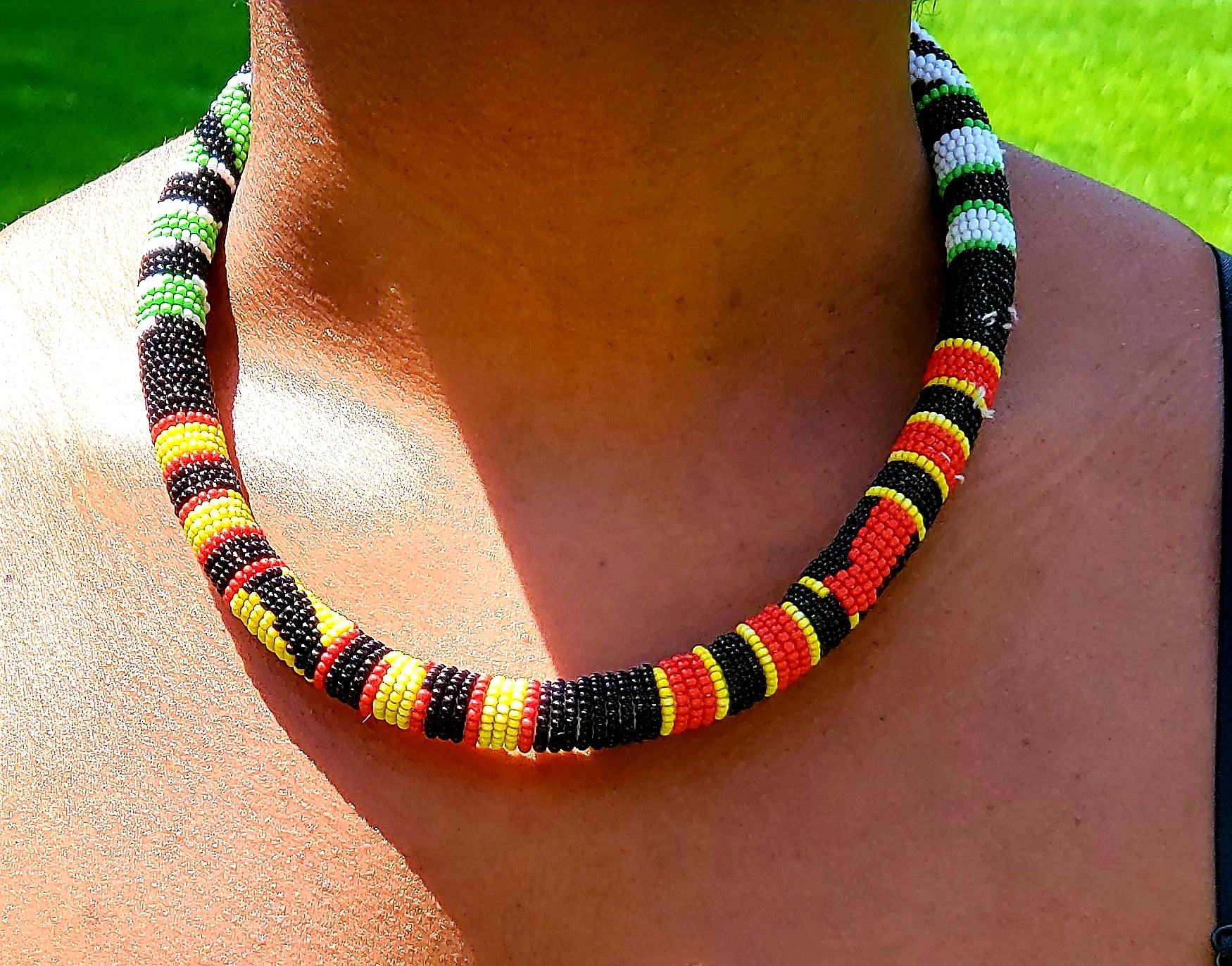 Black, red, yellow patterned Ghana necklace, with white and green pattern on the back side